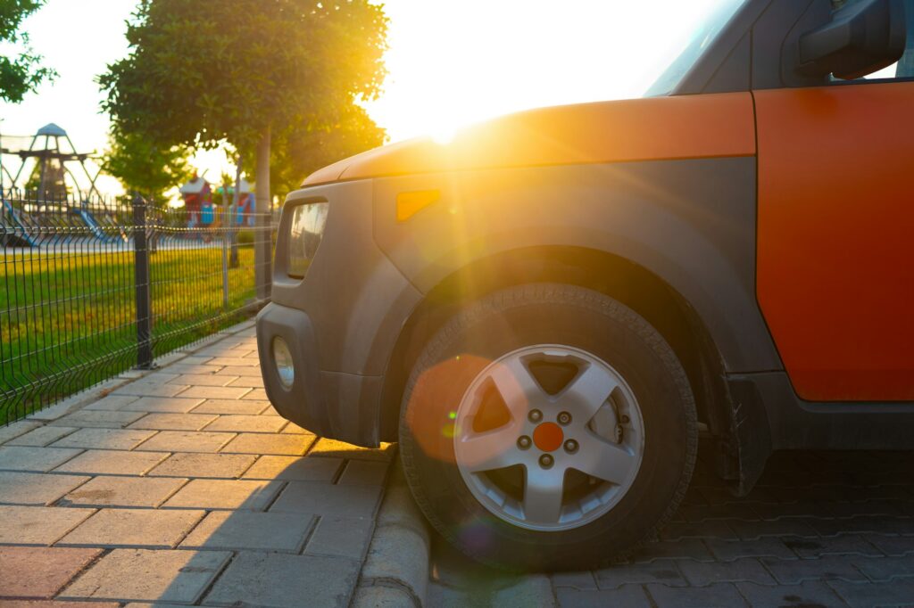 Close up of part of an orange car in sun beam