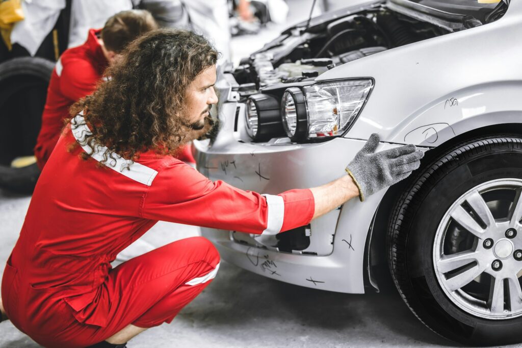 Mechanic garage auto workshop team working service repair fix damaged front bumper accident car